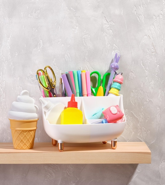 Stationery stand in the shape of a white bathtub Lots of pens pencils scissors Cold vanilla ice cream in a waffle cup