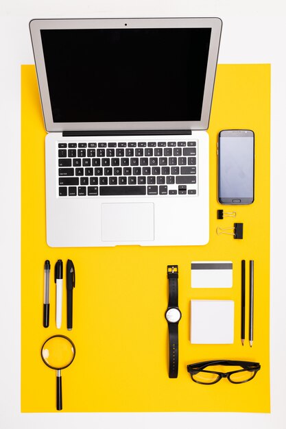 Elementi decorativi con laptop, carta di credito con mockup, telefono e lente d'ingrandimento si trovano sul tavolo