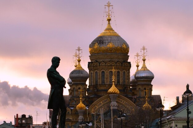Statue against church at sunset
