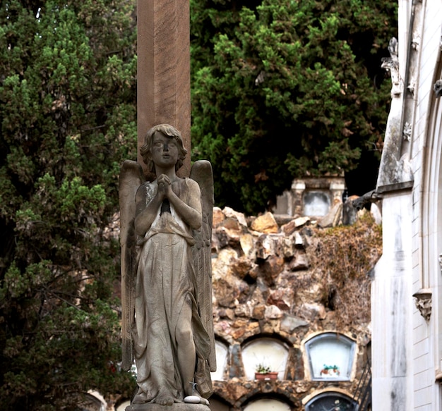 A statue of an angel stands in front of a cemetery.