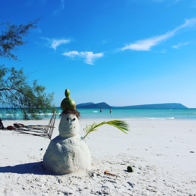 Statue on beach against blue sky