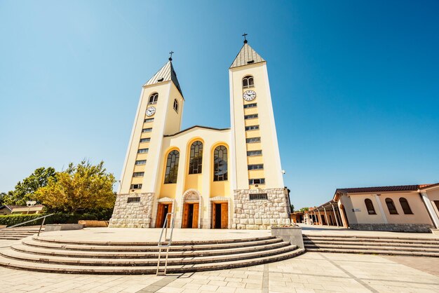 Photo statue of the blessed virgin mary holding a red rose while saint james church in medjugorje