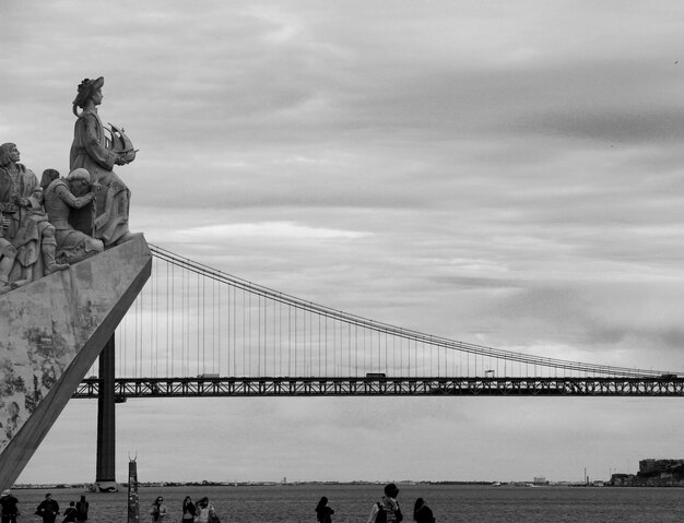 Statue of bridge over sea against cloudy sky