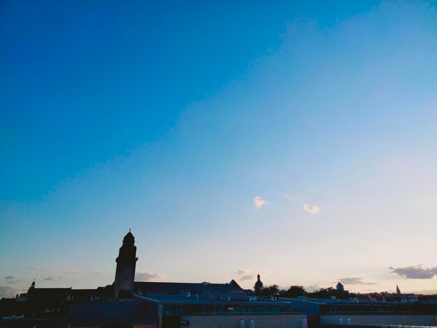 Statue in city against blue sky