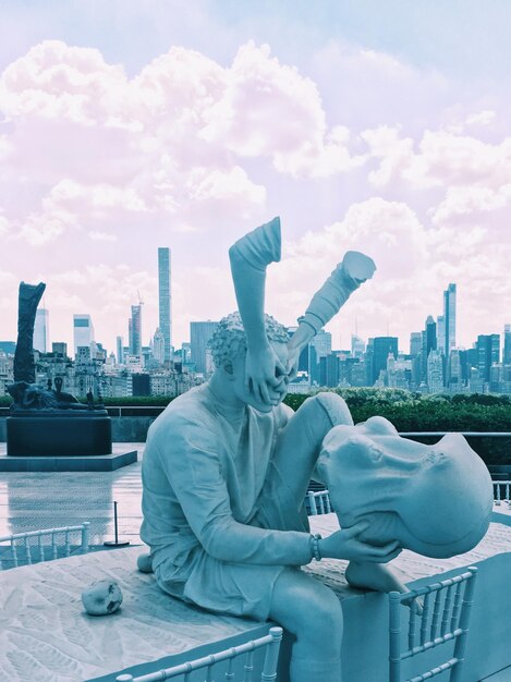 Photo statue in city against cloudy sky