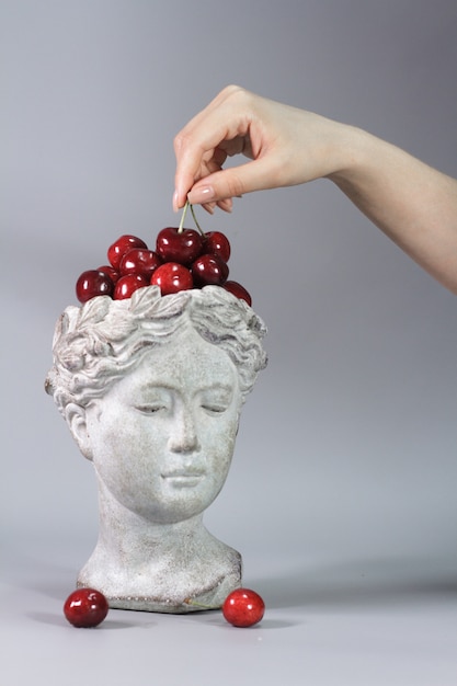 Statue of a Greek goddess head full of ripe cherries