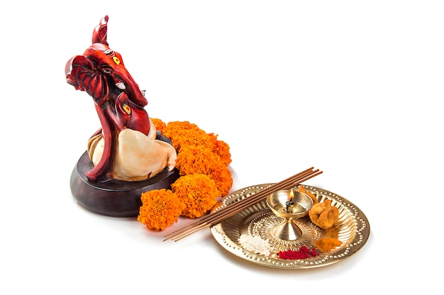 Statue of Hindu God Ganesha with Worship arrangement on white surface.