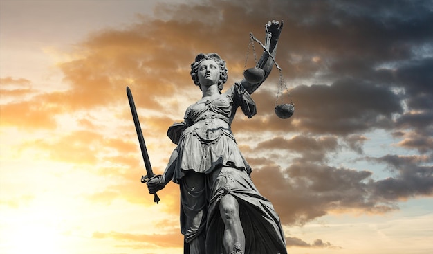Статуя правосудия - леди правосудия или Юстиция / Юстиция, римская богиня правосудия на фоне драматического облачного закатного неба. идеально подходит для макетов веб-сайтов и журналов