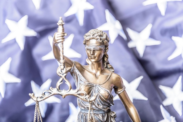 Photo the statue of justice themis or iustitia the goddess of justice blindfolded against a flag of the united states of america as a legal concept