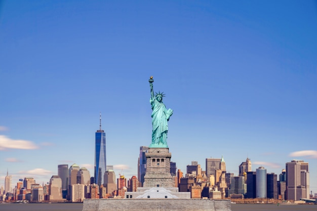 Foto la statua della libertà con il one world trade center edificio sul fiume hudson e lo sfondo del paesaggio urbano di new york, punti di riferimento di manhattan new york city.