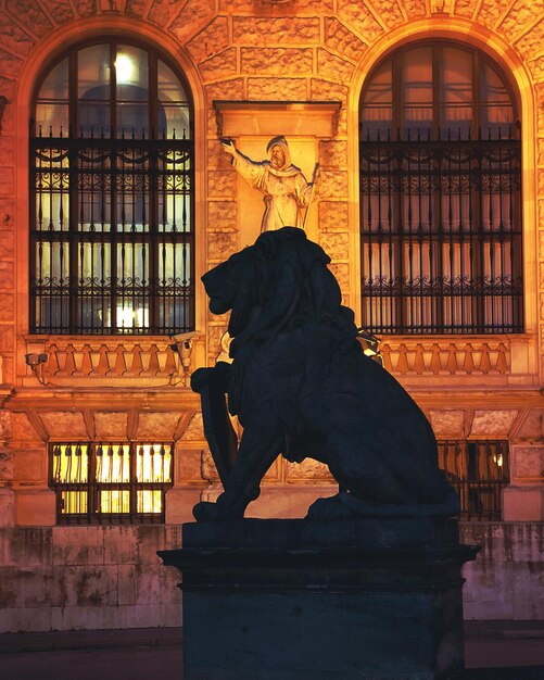 Statue of lion against lit building