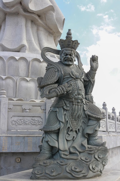 A statue of a man in a chinese hat stands in front of a building that says'king '