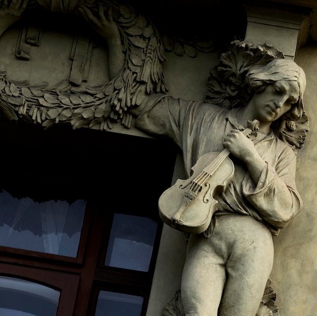 A statue of a man holding a guitar is outside a building.