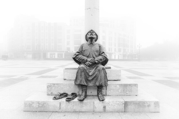 Photo a statue of a man sits in a foggy city.