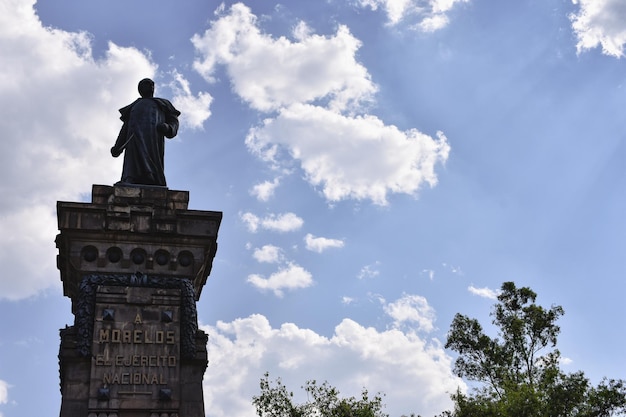 Photo a statue of a man stands in front of a blue sky with clouds