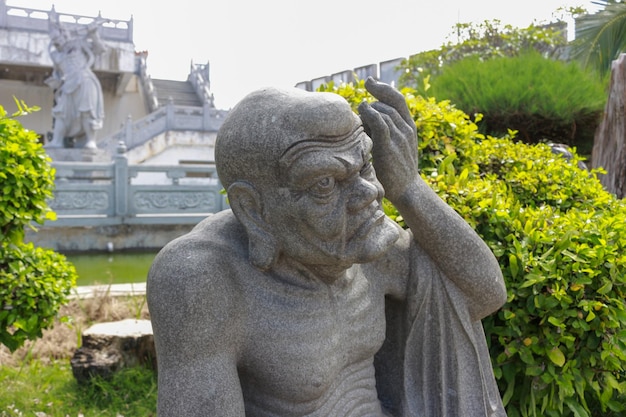 A statue of a man with a green bush in the background