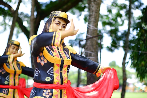 A statue of a man with a hat on is holding a red cloth.