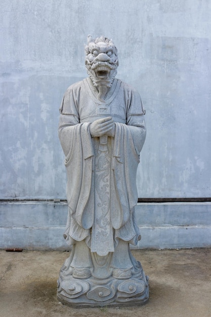 Photo a statue of a man with a mask on his face stands in front of a gray wall.