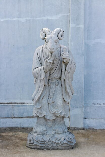 Photo a statue of a monk stands in front of a blue wall.