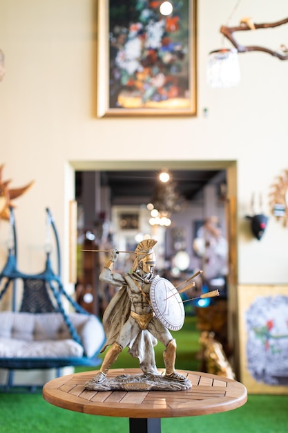 A statue of a roman warrior stands on a table in a living room.