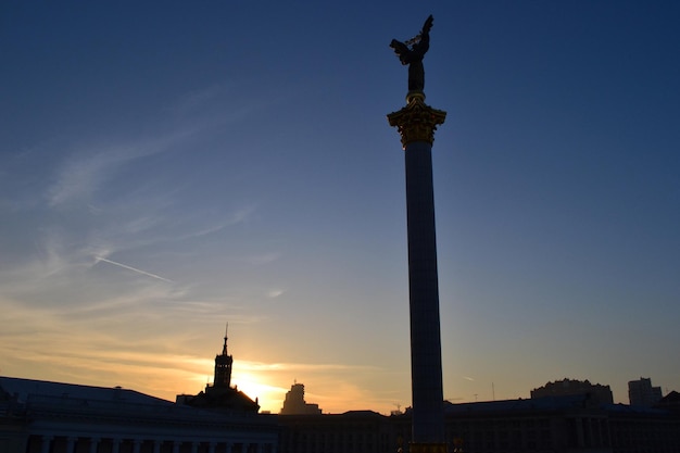 Statue at sunset sky over the city at sunset town silhouette in backlight