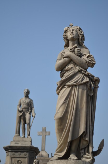 Foto una statua di una donna che tiene una croce e una croce sullo sfondo