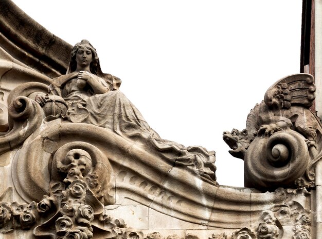 A statue of a woman sits on a balcony with a white background.