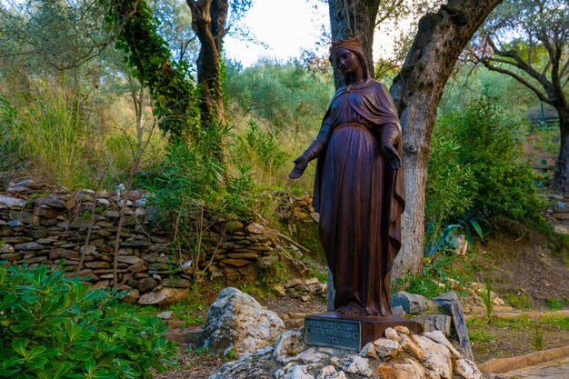 Статуя женщины с крестом возле дерева в Эфесе, Турция