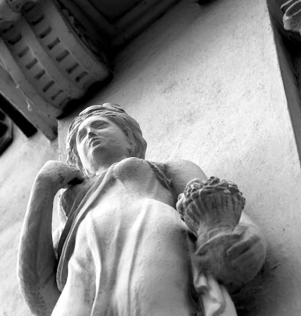 A statue of a woman with a shell on her arm is on a ledge.