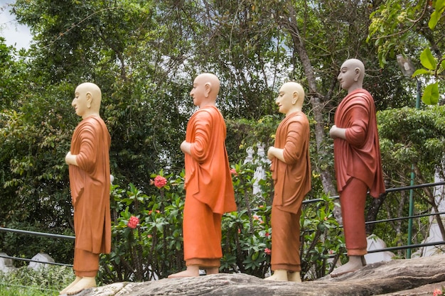 Statues of buddhas on a rock in front of a tree.