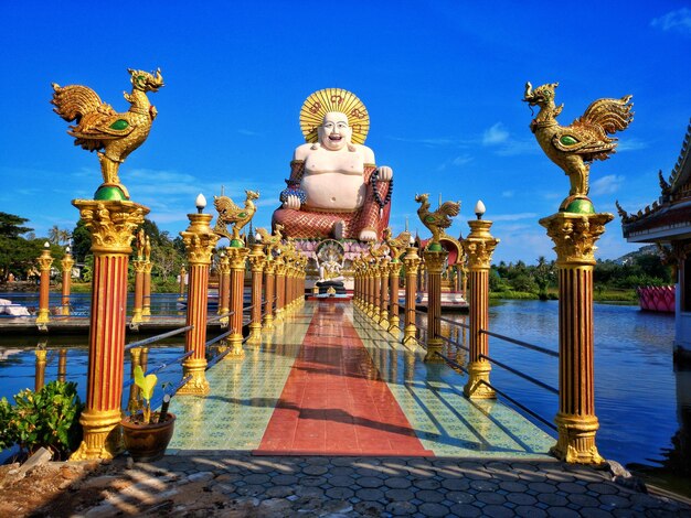 Statues by lake against blue sky