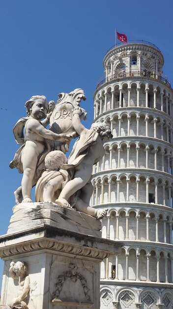 Foto statue e torre pendente di pisa contro un cielo blu limpido