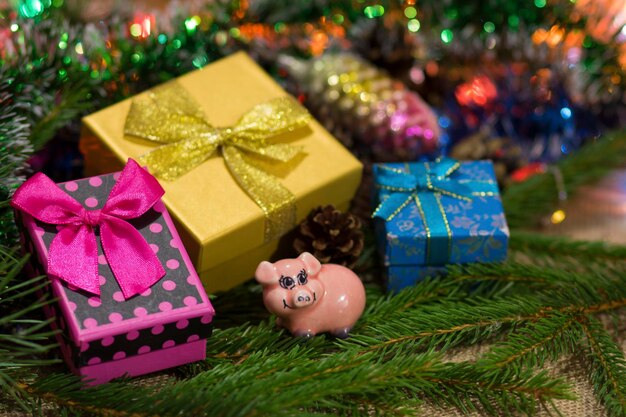 A statuette of a pig surrounded by boxes of Christmas presents sitting on sprigs of spruce