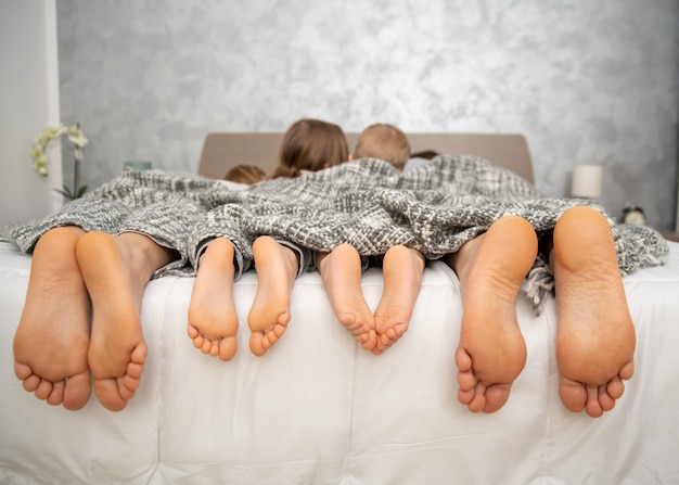 家にいる、ベッドの上に4組の足、親と子供