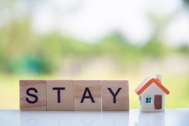 Stay home message made of wooden letters and miniature house