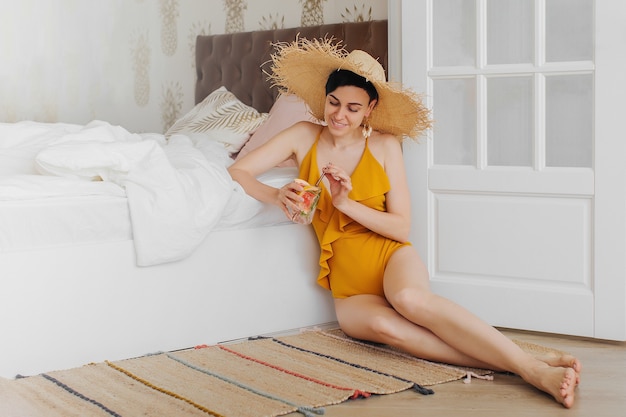 Stay Home, quarantine. Vacation canceled. Young woman in a yellow swimsuit on a bed in a hotel room.