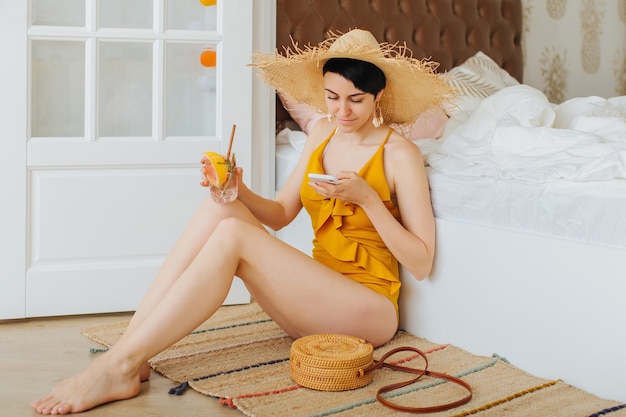 Stay Home, quarantine. Vacation canceled. Young woman in a yellow swimsuit on a bed in a hotel room.