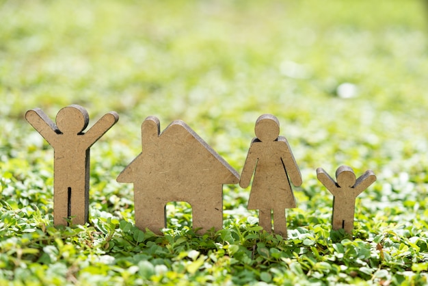 Resta a casa resta al sicuro concetto con la casa e la famiglia modello su erba verde fresca alla luce del sole del mattino