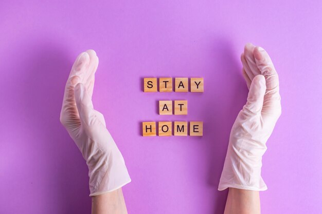 Stay at home text in hands in rubber gloves