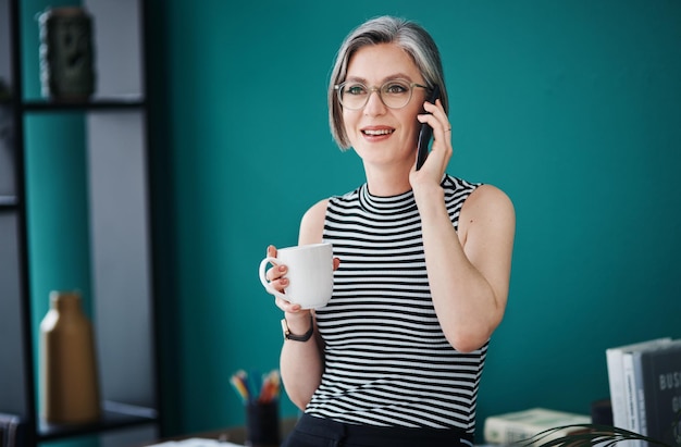 Foto rimani positivo e continua a dare il meglio di te foto di una donna d'affari che prende un caffè mentre parla al cellulare nel suo ufficio