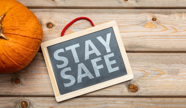 Stay safe message and thanksgiving pumpkin against wooden background covid 19 days
