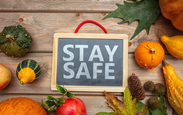 Photo stay safe message and thanksgiving pumpkins against wooden background covid 19 days