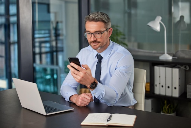 Staying ahead is about staying on call Cropped shot of a handsome mature businessman sending a text while working at his desk in the office