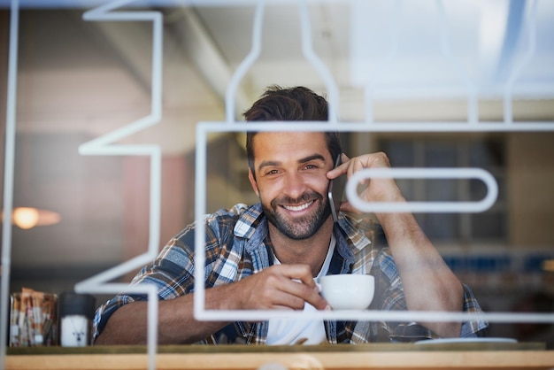 커피 휴식 시간 동안 연결 유지 좋아하는 카페에서 커피를 마시며 휴대폰에 응답하는 행복한 젊은 남자의 초상화