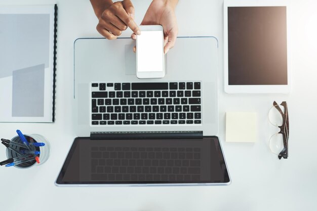 Staying in the loop with the touch of a button High angle shot of an unrecognizable woman sitting at her office desk scrolling through her smartphone