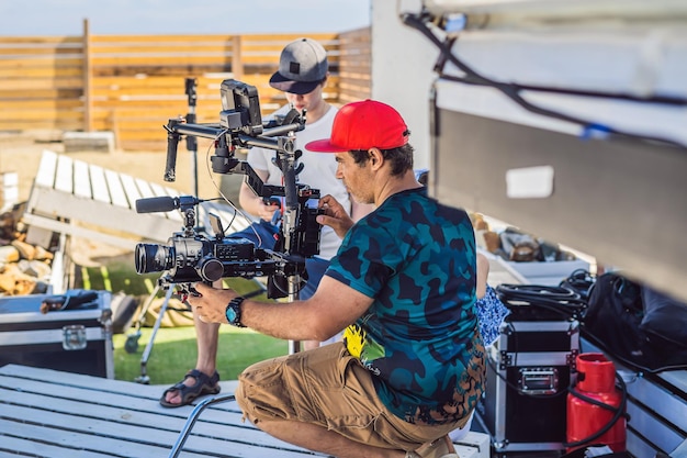 Steadicam operator and his assistant prepare camera and 3axis stabilizergimbal for a commercial shoot