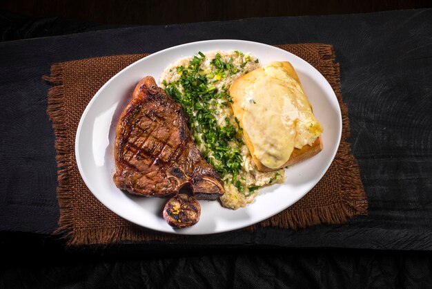 Steak beef cut with risotto, baked garlic and crostinni with melted cheese, top view.