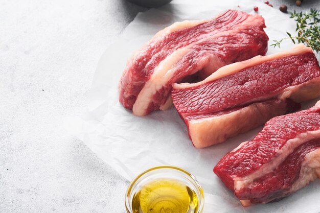 Steak beef Raw steak New York with rosemary and spices on black stone cutting board on light white stone background Top view Mock up