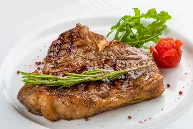 Steak bone with greens On a white plate