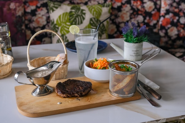 A steak and a bowl of food on a wooden cutting board